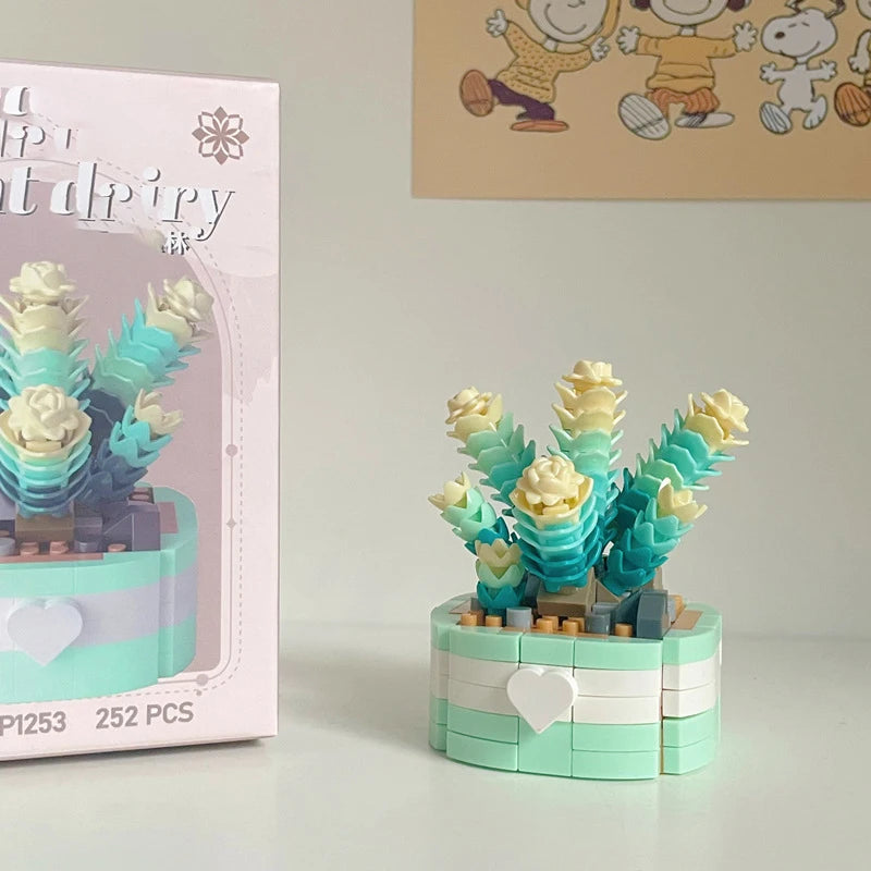 A miniature flower bouquet made of light blue and cream building blocks displayed next to its packaging.