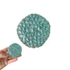 A translucent teal squishy bead stress ball with a textured, bubbly surface being held in a hand.