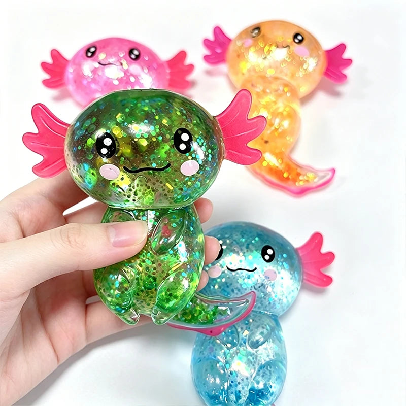 A hand holds a glitter axolotl squishy stress relief toy featuring pink, orange, and blue colors.
