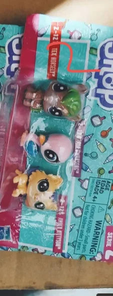 A plastic packaging shows three small animal figures, including a brown and green creature, for sale.