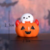 An orange pumpkin figurine with a white bear face and red ears, displayed against a blurred background.