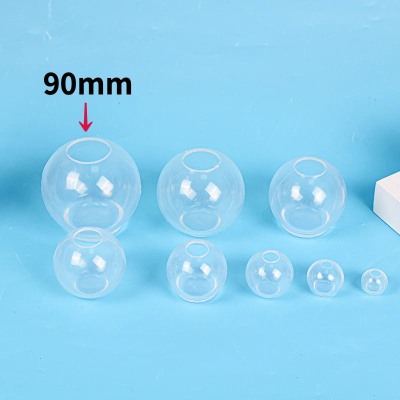 A collection of clear silicone sphere molds for resin crafting, showing various sizes and a dimension marker.