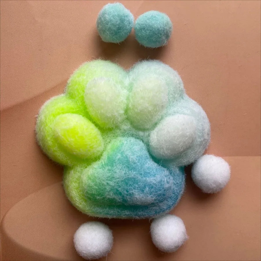A soft, pastel green and blue cat paw squishy fidget toy made of mochi-like material.