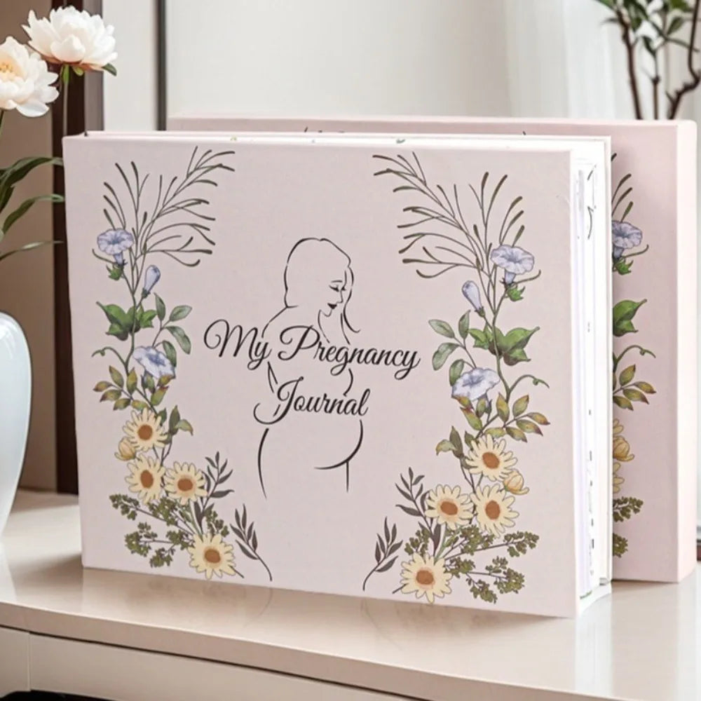 A pink pregnancy journal featuring botanical illustrations of flowers and a silhouette of a pregnant woman.