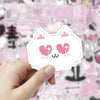 A hand holds a pink and white outline sticker featuring a cute, smiling fox face with pink hearts.