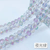 A close-up of a strand of iridescent crystal beads with an AB coating, showing various shades of purple and green light.
