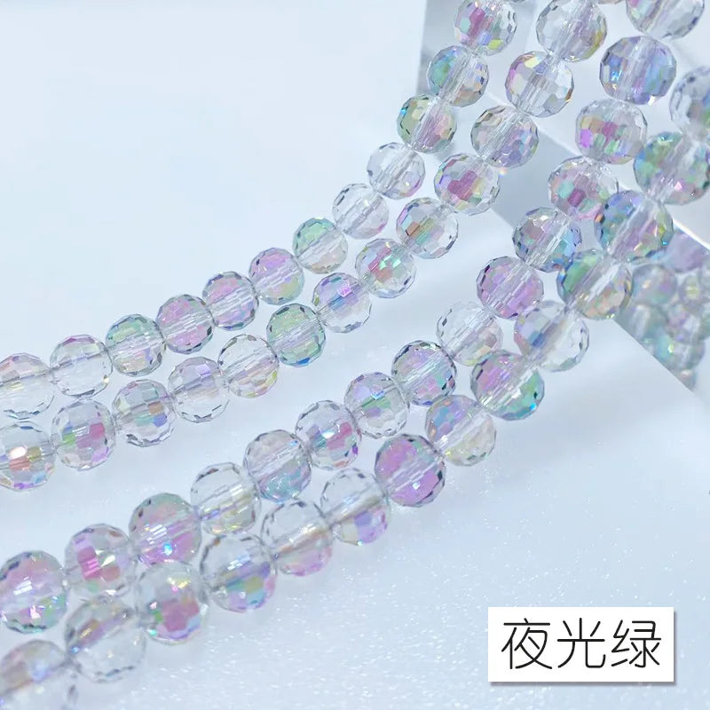 A close-up of a strand of iridescent crystal beads with an AB coating, showing various shades of purple and green light.