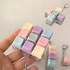 A hand holds a clear plastic keyboard fidget toy with various pastel colored silicone keys and attached keychains.