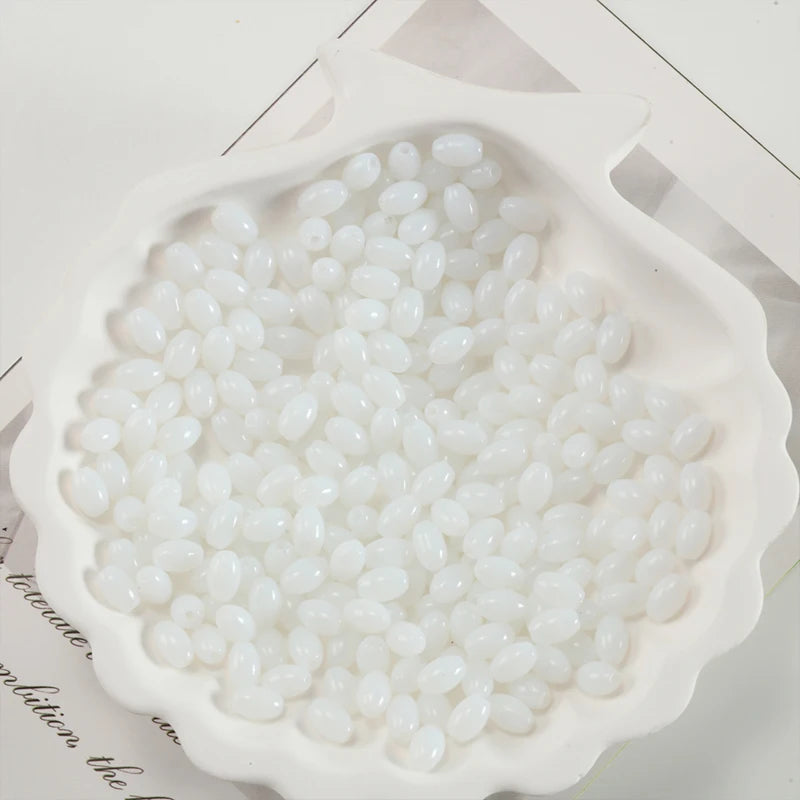 White oval glass rice grain beads for jewelry making displayed in a mold.