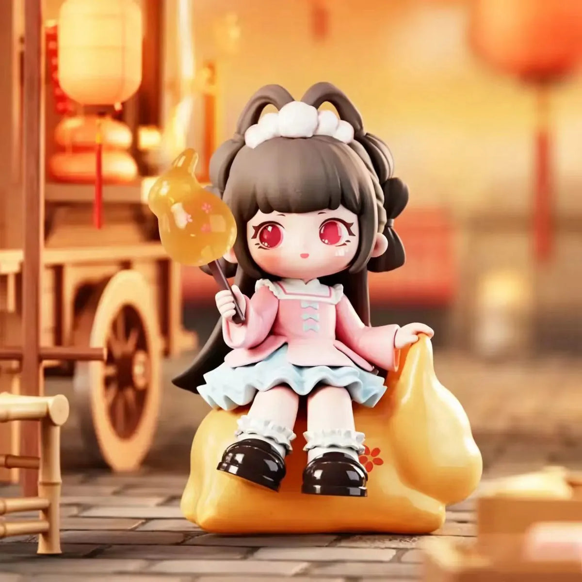 A collectible figurine of a girl with dark hair and pink clothing sitting on a yellow, blob-like base.