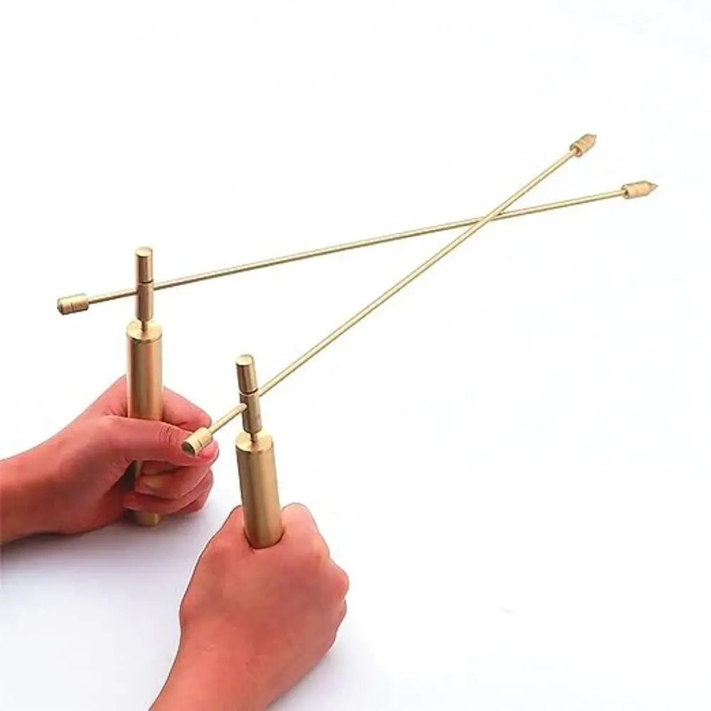 Hands holding and manipulating thin brass dowsing rods for paranormal investigation