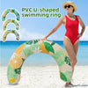 A woman is holding a yellow and green PVC U-shaped swimming ring on a beach with blue water in the background.