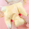 A hand holds a large, pale yellow cheese-shaped squishy stress relief toy packaged in clear plastic.