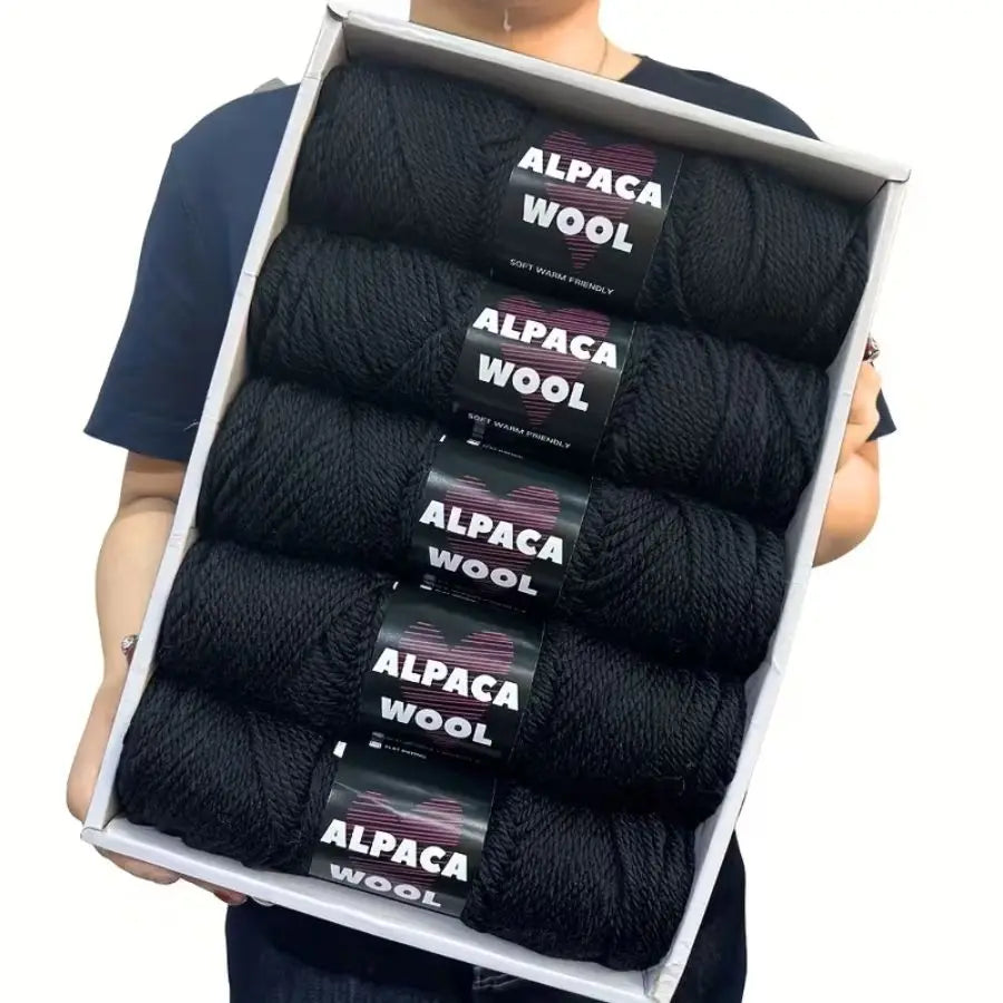 A pack of five black alpaca wool yarns for knitting and crochet displayed in a white box.