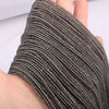 A close-up of dark gray faceted natural stone beads threaded onto a string, shown on a hand.