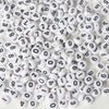 A pile of small white acrylic number beads with black numbers scattered on a white surface.