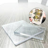 A clear silicone gel printing plate is shown on a wooden surface next to a small piece of art.