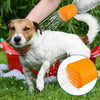 A dog is being washed with an orange silicone pet shower head outdoors.
