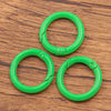 A set of four bright green metal O-ring spring clasps for DIY jewelry and keychains resting on a wooden surface.