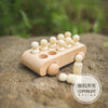 A wooden train set with numbered cars is placed on a stone surface.