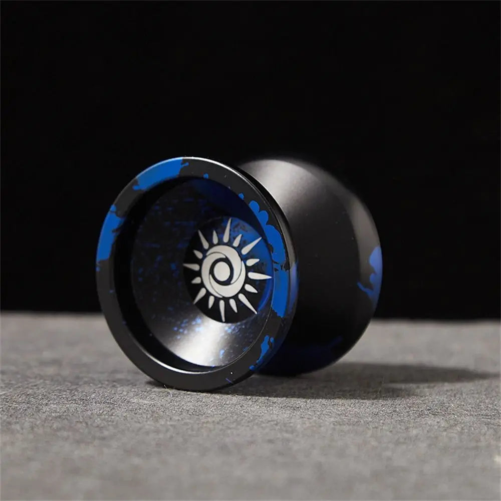 A black metal yo-yo with blue accents is shown resting on a gray surface.