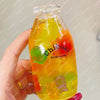 A hand holds a clear plastic bottle filled with colorful liquid and squishy stress balls for sensory relaxation.