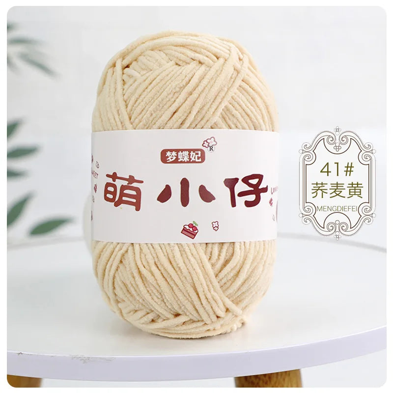 A ball of light beige chenille yarn labeled with Chinese characters for knitting and crochet.