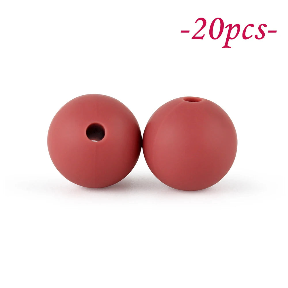 Two round, reddish-pink silicone beads are shown against a white background.