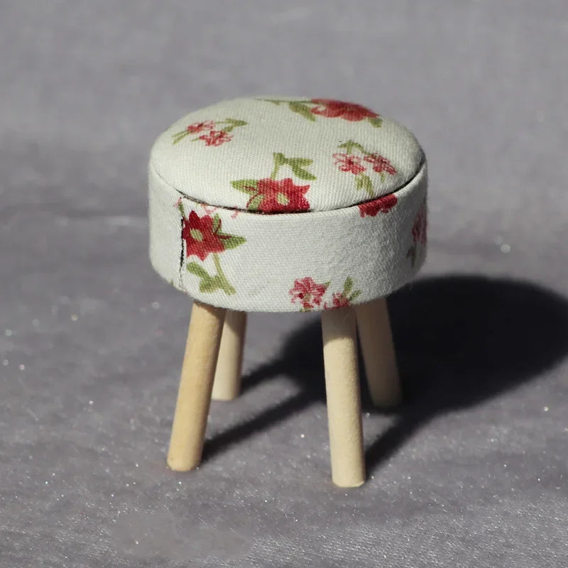 A miniature sofa and pillow set for a dollhouse featuring a light green fabric with red floral patterns.