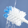 A white and blue cleaning brush is shown under running water, demonstrating its ability to wash away dirt.