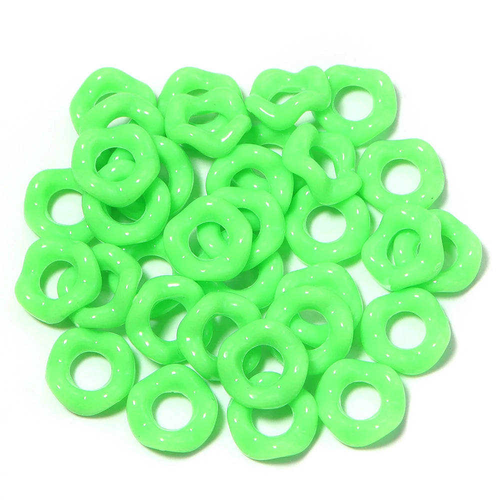 A pile of bright lime green acrylic doughnut spacer beads for jewelry making