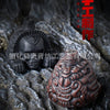 A dark bronze Aztec death whistle skull artifact resting on rough stone.