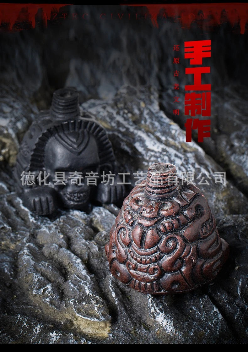 A dark bronze Aztec death whistle skull artifact resting on rough stone.