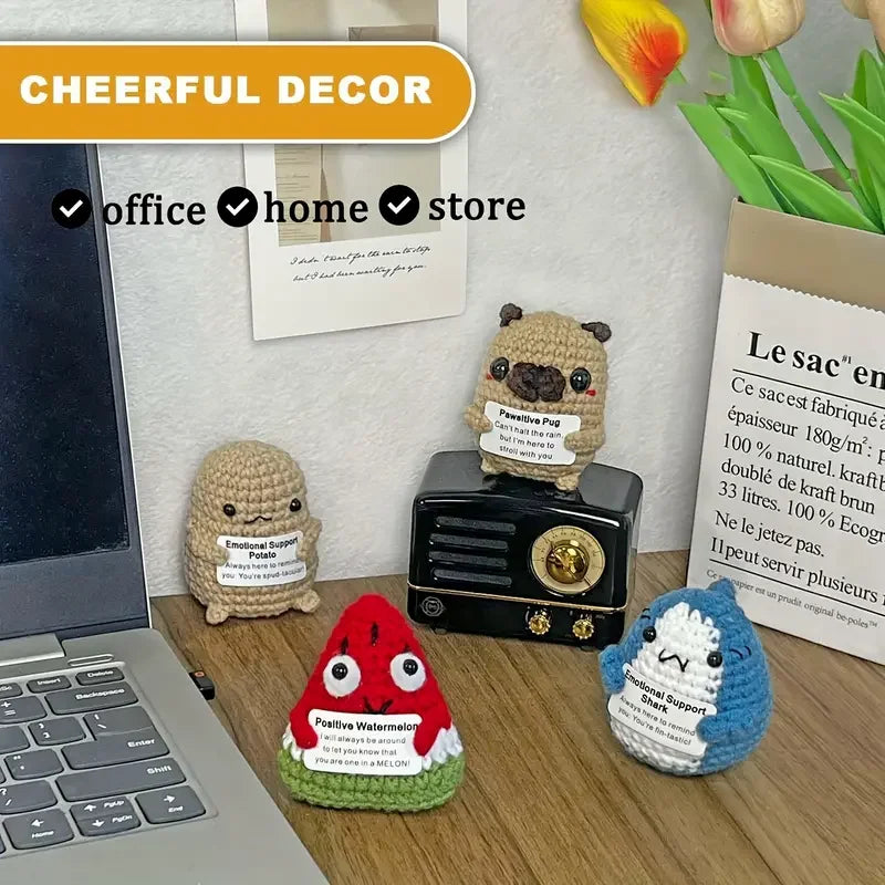 A collection of handcrafted crochet shark dolls and a laptop on a wooden desk.
