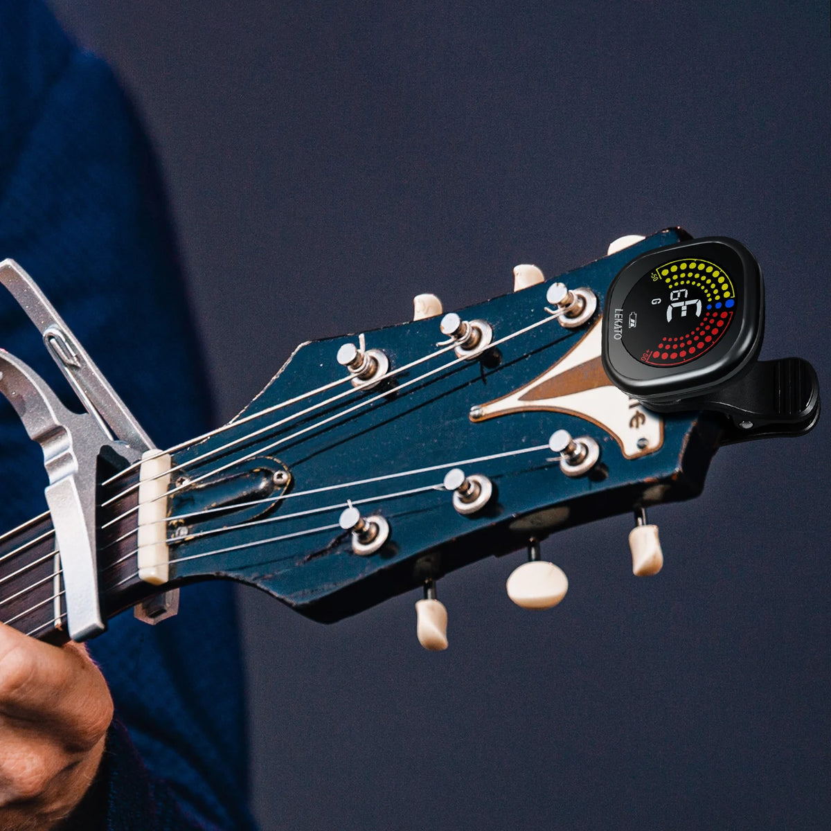 Nahaufnahme einer dunkelblauen Gitarre mit einem Clip-On-Stimmgerät am Kopf)}