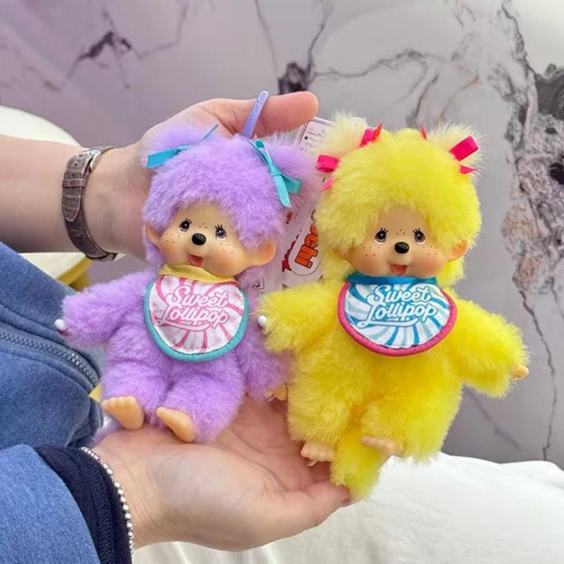 A hand holds two fluffy plush cartoon characters, one purple and one yellow, resembling a kawaii charm.