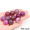 A collection of polished pink agate crystal spheres held in a hand.
