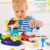 A toddler plays with a small barber kit featuring various tools like scissors and combs on a white table.