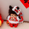 A small brown Monchhichi plush toy with white fur and red clothing, displayed against a white background.