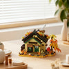 A miniature forest cabin building block set featuring a house, greenhouse, and windmill on a wooden surface.
