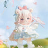 A cute figurine of a girl with pink hair and white dress, featuring light blue accents and a pink bow, standing in a grassy o