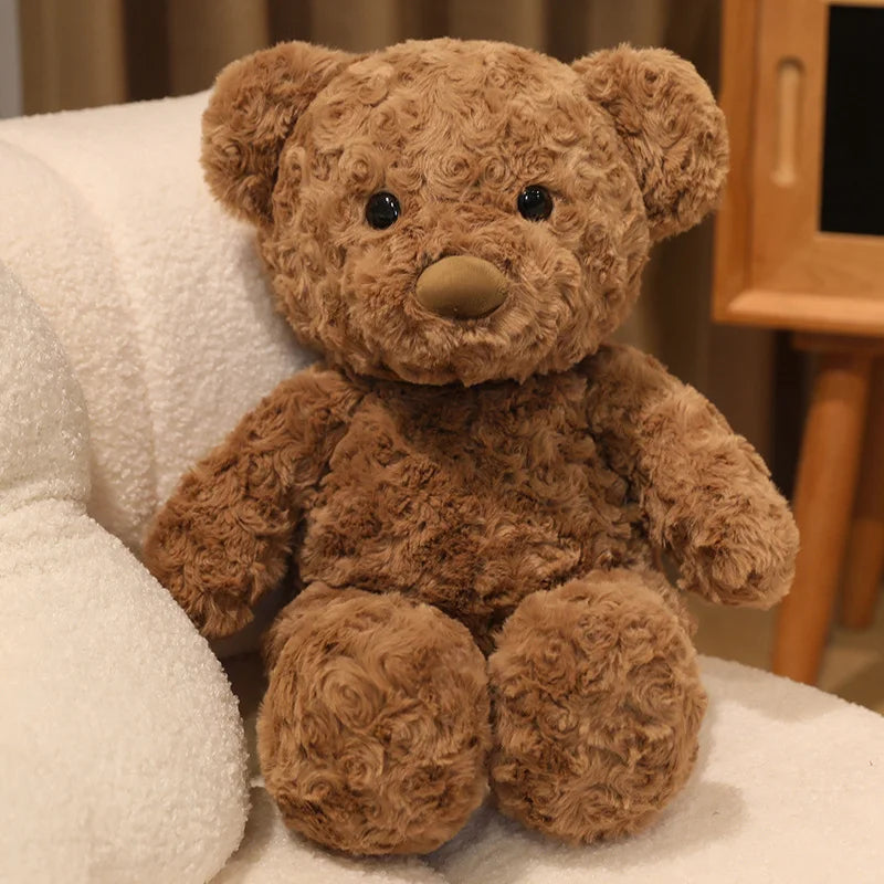 A brown teddy bear plush toy sitting on a white towel.