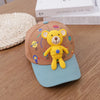 A yellow bear baseball cap featuring a 3D design, resting on a wooden surface next to some books.