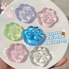 A collection of pink, blue, and green crystal cat claw squishy toys on a white plate.