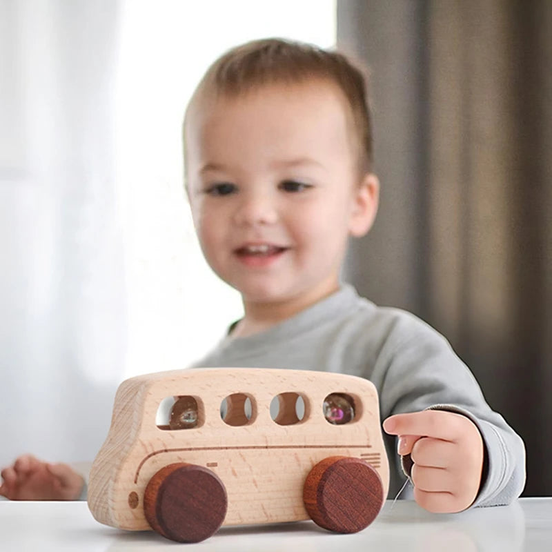 A toddler is holding a wooden Montessori push cart toy shaped like a car or bus.