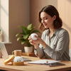 A woman is holding a white dumpling squishy stress ball with a steamer basket on a wooden desk.