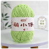 A ball of light green chenille yarn with Chinese characters on the label, displayed on a white table.