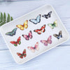 A white rectangular plate features a collection of colorful butterfly stickers on a light blue wooden surface.