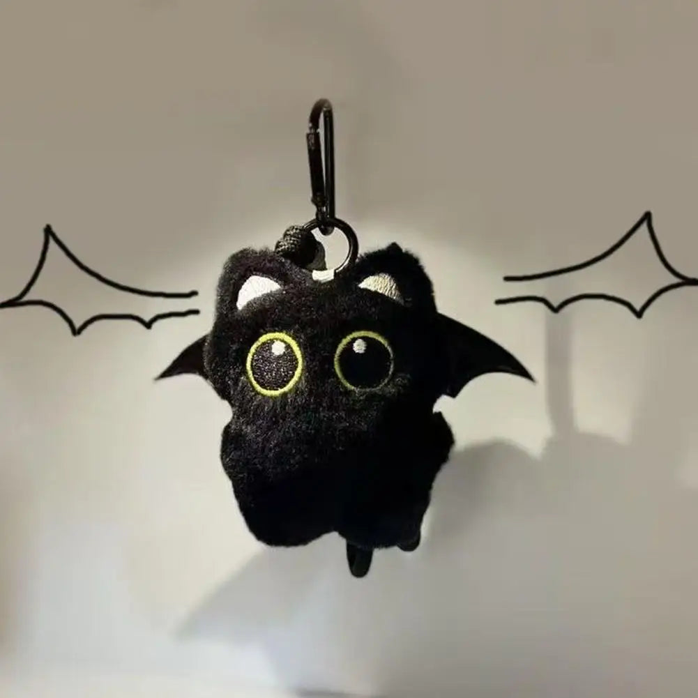 A black plush cat keychain with yellow eyes is hanging against a light background.