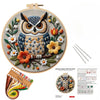 A DIY embroidery kit featuring an owl and floral design on a canvas with thread and tools.